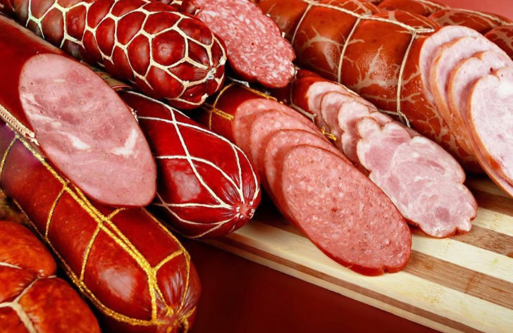 Cooked and smoked beef sausages on a board — thick sticks, bias cut and sliced.